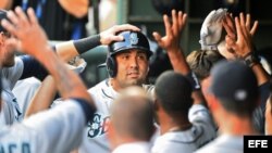 Kendrys Morales (c) de los Marineros de Seattle celebra con sus compañeros en el dugout tras batear el primero de dos jonrones ante los Vigilantes de Texas. 